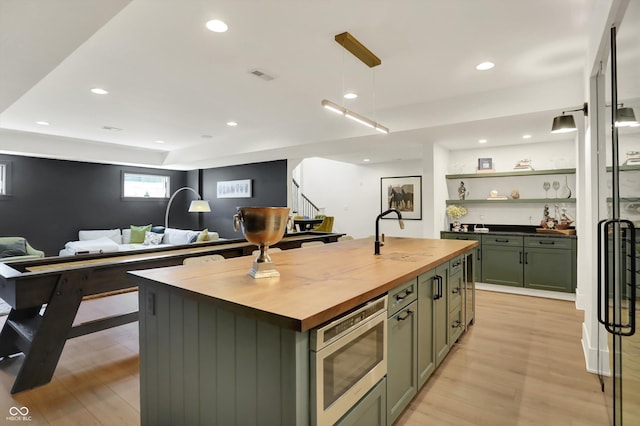5130 Melbourne Pl, Zionsville, IN 46077 - kitchen featuring butcher block counters, green cabinets, stainless steel microwave, a sink, and light wood-type flooring