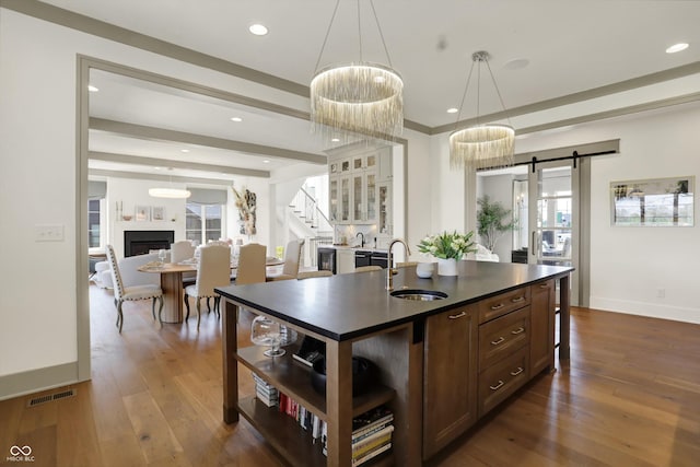 5130 Melbourne Pl, Zionsville, IN 46077 - kitchen with dark countertops, a sink, a barn door, open shelves, and dark wood finished floors