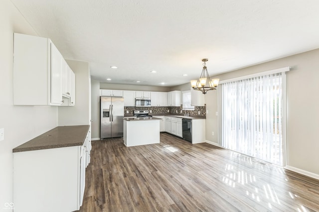 4747 Summit Lake Pl, Indianapolis, IN 46239 - kitchen featuring white cabinetry, appliances with stainless steel finishes, dark countertops, decorative backsplash, and an inviting chandelier