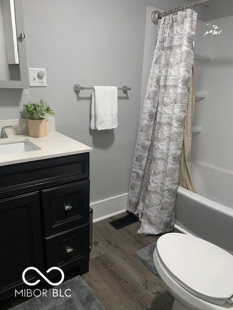 bathroom with shower / bath combo, baseboards, wood finished floors, toilet, and vanity