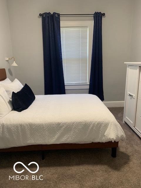 bedroom with baseboards and dark carpet