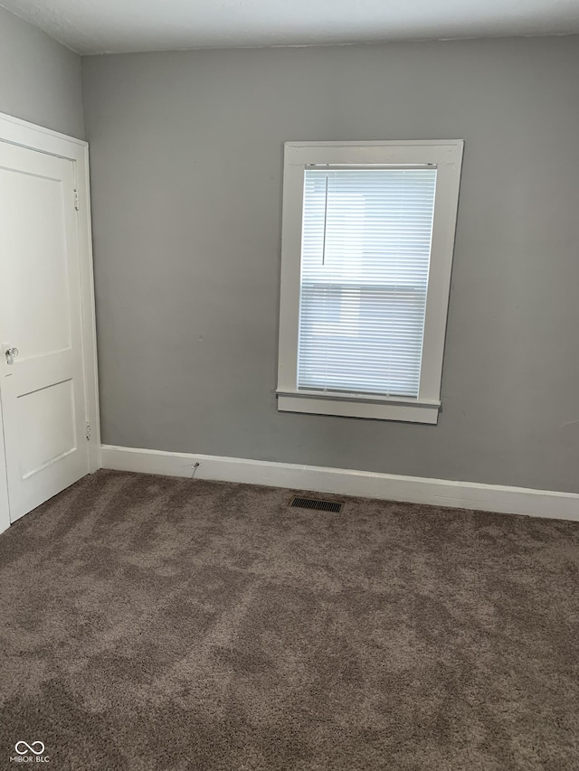 empty room with carpet flooring, baseboards, and visible vents