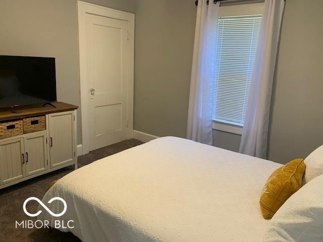 bedroom featuring baseboards and dark carpet