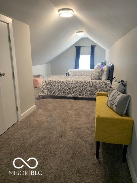 bedroom featuring baseboards, lofted ceiling, and carpet flooring