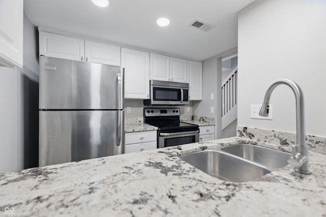 6059 S Bay Dr, Indianapolis, IN 46250 - kitchen featuring a sink, visible vents, white cabinets, light stone countertops, and appliances with stainless steel finishes
