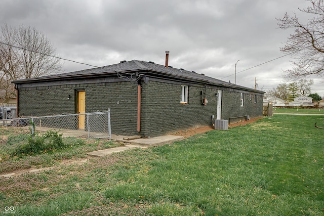2134 Dawson St, Indianapolis, IN 46203 - view of property exterior with a lawn, brick siding, fence, and central AC unit