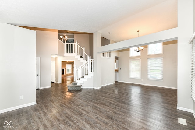 unfurnished living room featuring high vaulted ceiling, a notable chandelier, and baseboards