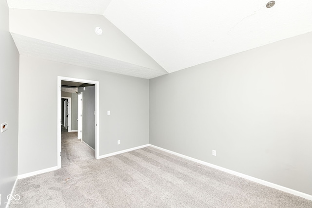 empty room with light carpet, baseboards, and lofted ceiling
