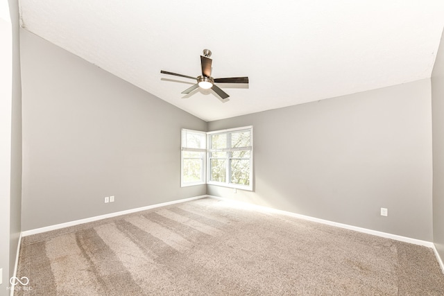 carpeted empty room with ceiling fan, vaulted ceiling, and baseboards