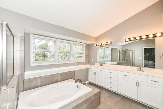 full bathroom featuring a garden tub, vaulted ceiling, a sink, a stall shower, and double vanity
