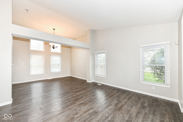 unfurnished room featuring dark wood-type flooring, baseboards, a chandelier, and vaulted ceiling