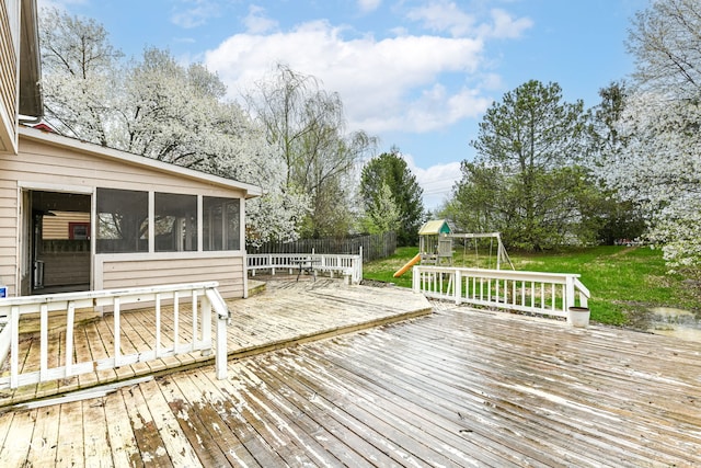 wooden deck with a yard, fence, a playground, and a sunroom
