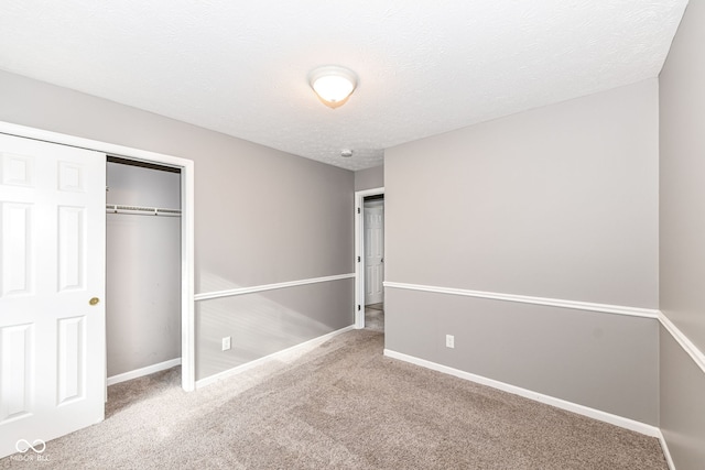 unfurnished bedroom featuring carpet floors, baseboards, a closet, and a textured ceiling