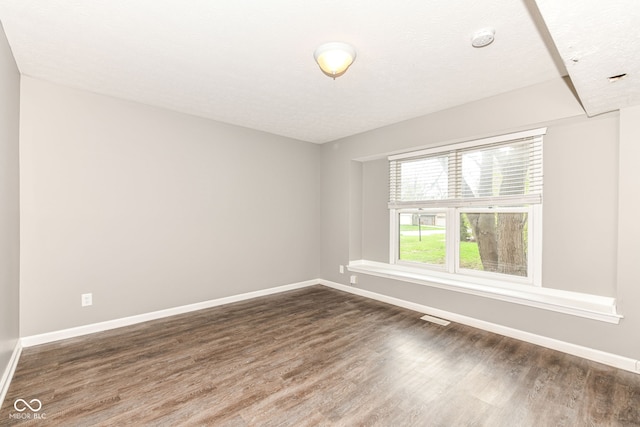 spare room with dark wood-type flooring, baseboards, and visible vents
