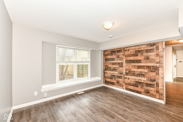 spare room featuring visible vents, baseboards, wood finished floors, and a textured ceiling