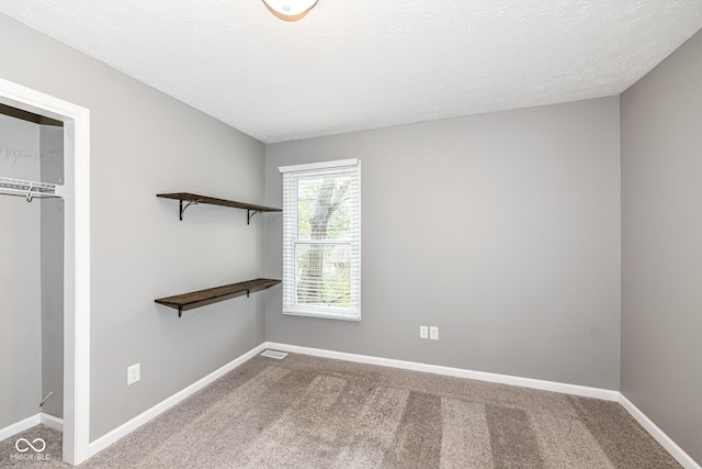 unfurnished bedroom featuring a textured ceiling, a closet, baseboards, and carpet
