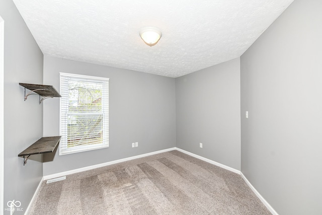 carpeted empty room featuring a textured ceiling, baseboards, and visible vents