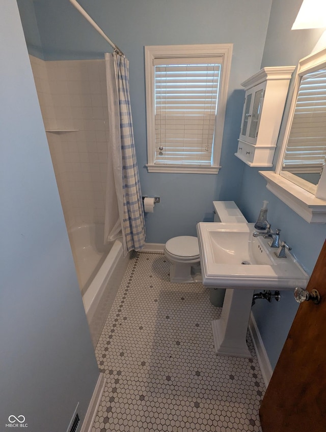full bathroom with tile patterned floors, toilet, shower / tub combo with curtain, a sink, and baseboards