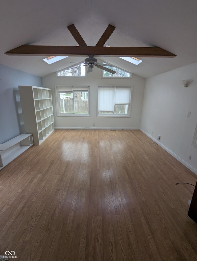 unfurnished living room with a ceiling fan, lofted ceiling with skylight, and wood finished floors