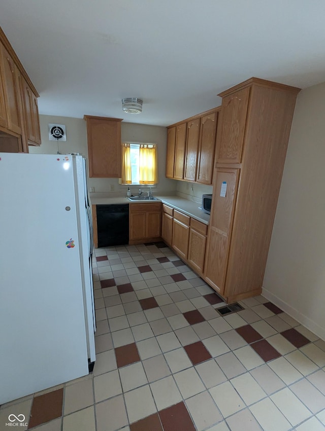 kitchen with light countertops, a sink, freestanding refrigerator, black dishwasher, and visible vents