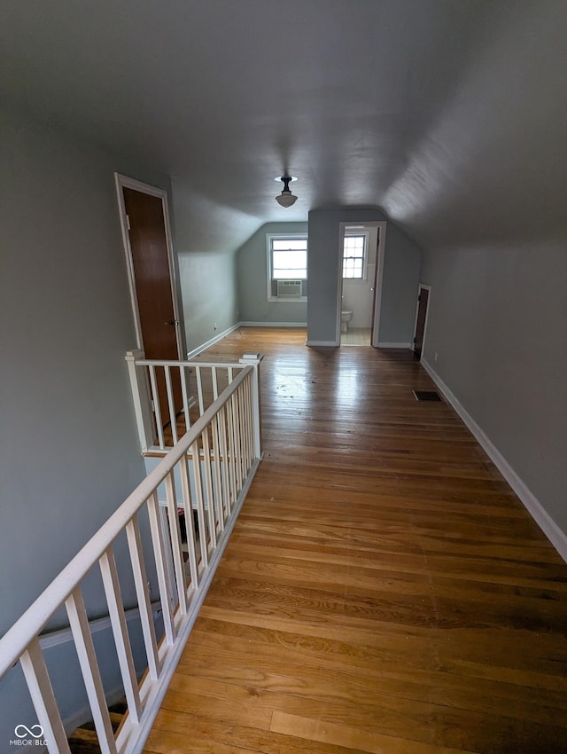 additional living space featuring baseboards, visible vents, hardwood / wood-style flooring, and vaulted ceiling