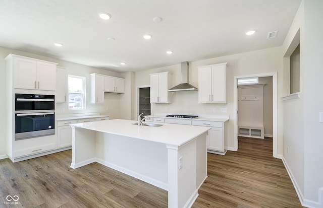 3241 Fawn Cir, Brownsburg, IN 46112 - kitchen with wall chimney range hood, a sink, a kitchen island with sink, light wood-type flooring, and white cabinets