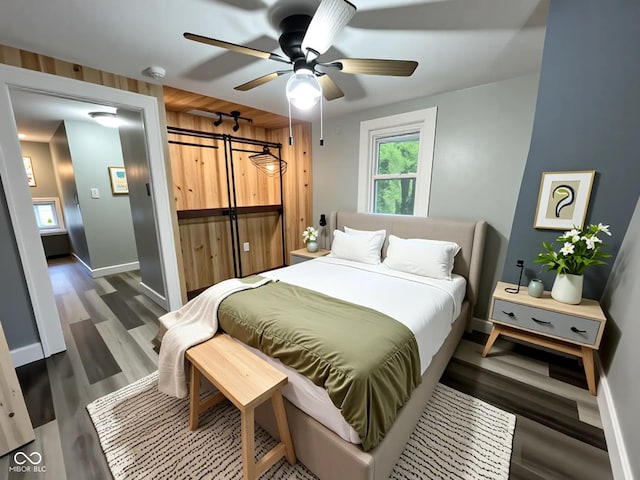1627 E 8th St, Anderson, IN 46012 - bedroom with a closet, a barn door, baseboards, ceiling fan, and wood finished floors