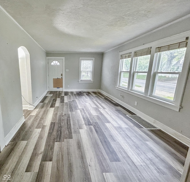 1627 E 8th St, Anderson, IN 46012 - unfurnished living room featuring wood finished floors, a textured ceiling, visible vents, arched walkways, and baseboards