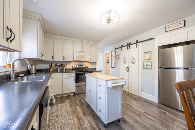 kitchen with a kitchen island, a barn door, a sink, dark wood-style floors, and stainless steel appliances