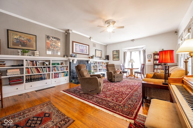 living room featuring ceiling fan, ornamental molding, hardwood / wood-style floors, and visible vents