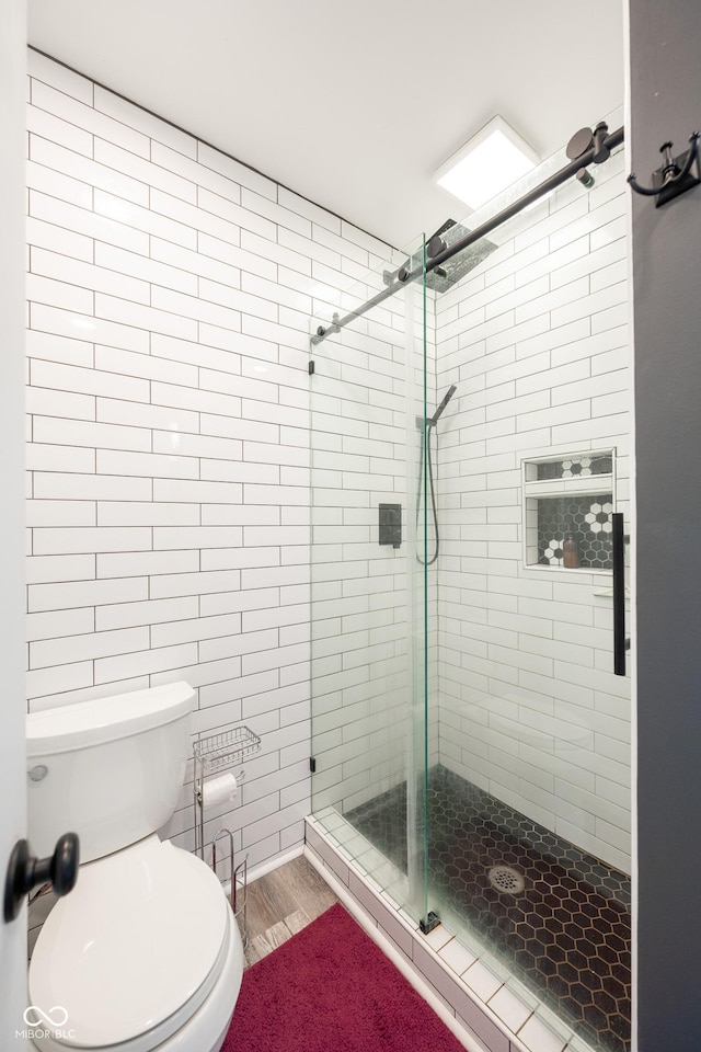 bathroom featuring a shower stall, toilet, and wood finished floors