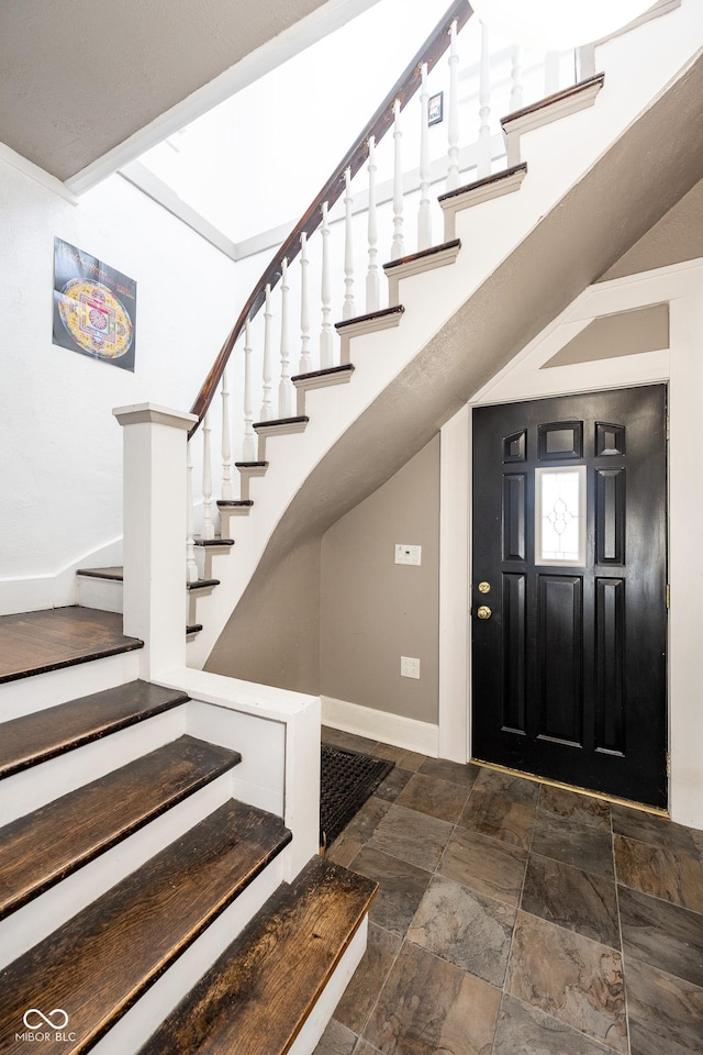 entrance foyer with baseboards, stairs, and stone finish flooring