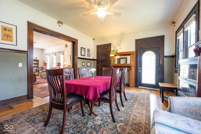 dining space featuring baseboards, ornamental molding, a ceiling fan, and wood finished floors