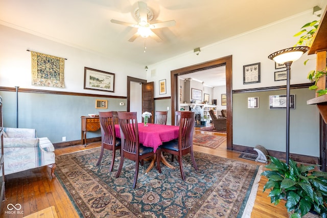 dining space with crown molding, a ceiling fan, baseboards, and wood finished floors