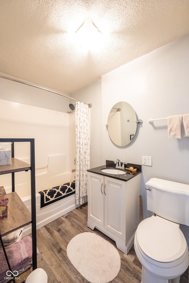 bathroom with toilet, a textured ceiling, wood finished floors, and vanity
