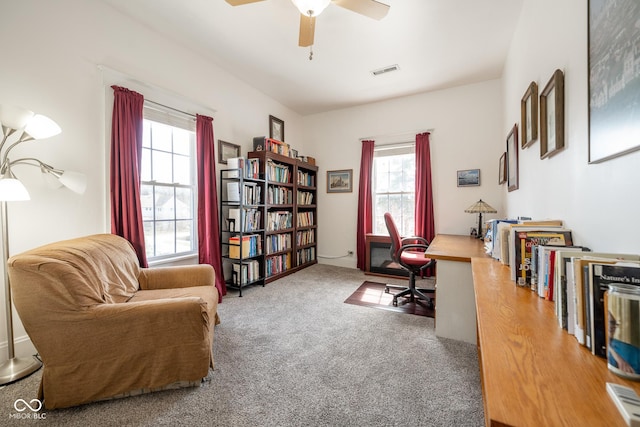carpeted office with visible vents, a ceiling fan, and a healthy amount of sunlight