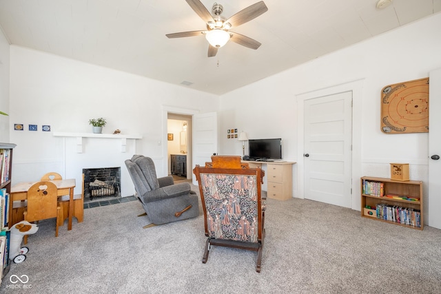 living area featuring carpet flooring, a ceiling fan, a fireplace with flush hearth, and visible vents