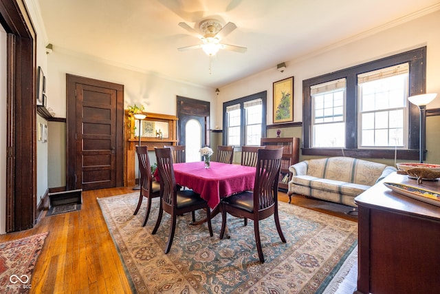 dining area with crown molding, baseboards, a ceiling fan, and hardwood / wood-style flooring