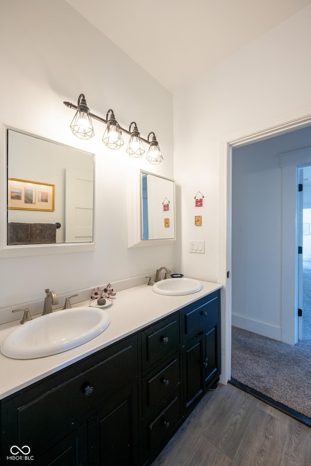 bathroom with double vanity, a sink, and wood finished floors