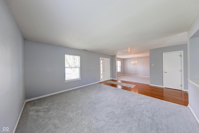 5989 Ashmore Ln, Carmel, IN 46033 - unfurnished living room featuring carpet floors, a chandelier, and baseboards