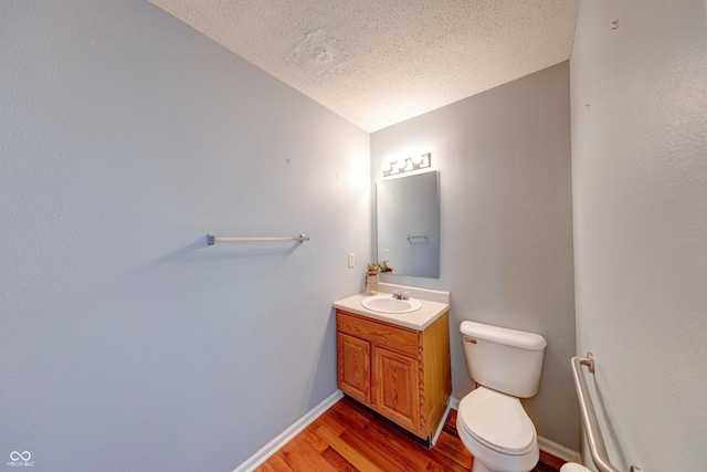 5989 Ashmore Ln, Carmel, IN 46033 - half bathroom with wood finished floors, a textured ceiling, vanity, toilet, and baseboards