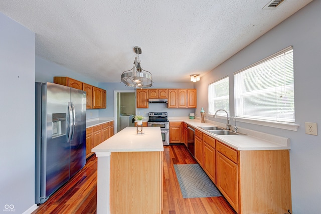 5989 Ashmore Ln, Carmel, IN 46033 - kitchen with appliances with stainless steel finishes, a sink, under cabinet range hood, a textured ceiling, and a kitchen island