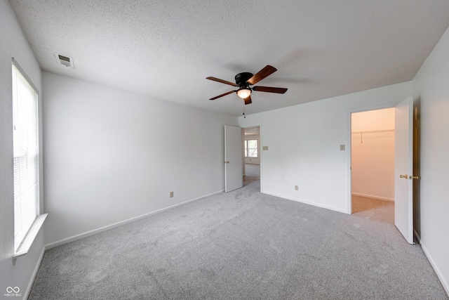 5989 Ashmore Ln, Carmel, IN 46033 - unfurnished bedroom with carpet floors, a walk in closet, baseboards, ceiling fan, and a textured ceiling