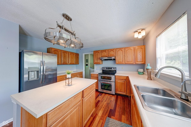 5989 Ashmore Ln, Carmel, IN 46033 - kitchen featuring appliances with stainless steel finishes, a sink, under cabinet range hood, dark wood-style flooring, and a textured ceiling