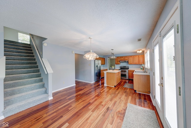 5989 Ashmore Ln, Carmel, IN 46033 - kitchen featuring stainless steel appliances, light countertops, a kitchen island, a chandelier, and under cabinet range hood