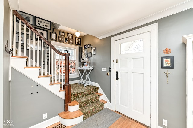 foyer with crown molding, baseboards, wood finished floors, and stairway