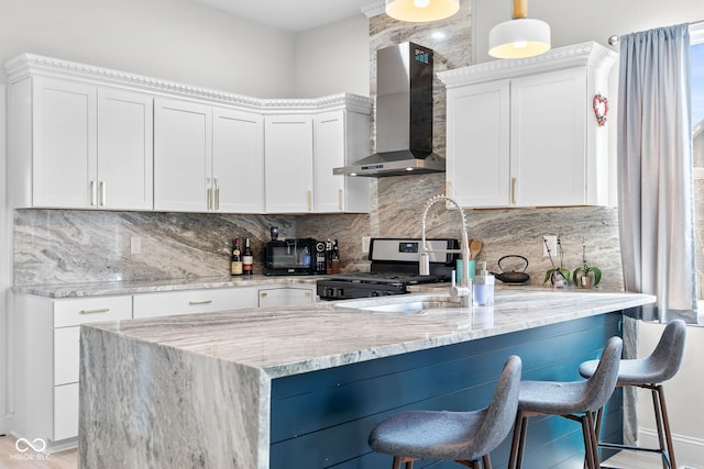358 Terrace Ave, Indianapolis, IN 46225 - kitchen featuring light stone countertops, wall chimney exhaust hood, stainless steel range with gas cooktop, a breakfast bar area, and backsplash