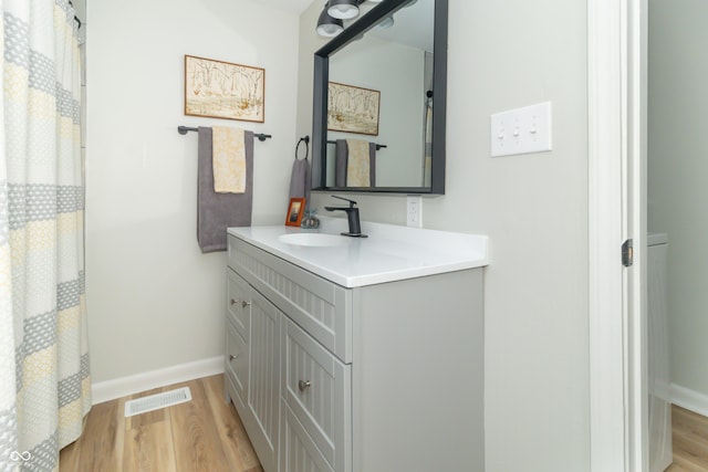 bathroom featuring visible vents, a shower with shower curtain, baseboards, wood finished floors, and vanity