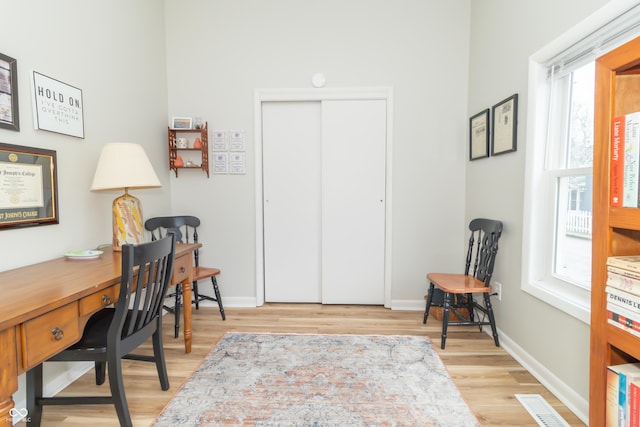 home office with baseboards, light wood-type flooring, and visible vents
