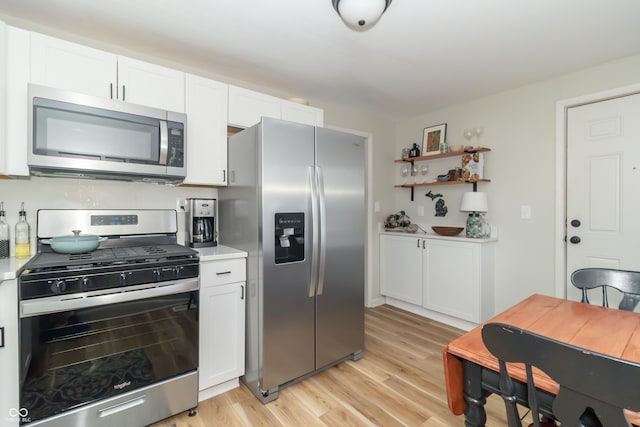 kitchen featuring light countertops, white cabinets, appliances with stainless steel finishes, open shelves, and light wood-type flooring